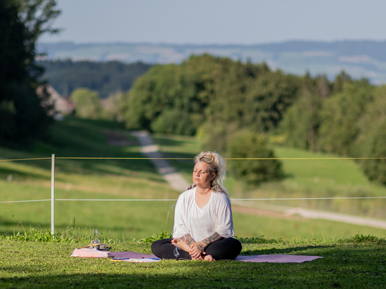 Frau sitzt in Yogapose und macht Achtsamkeit Wahrnehmungsübung