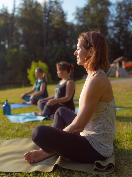 Personen in Yoga Pose auf einer grünen Wiese